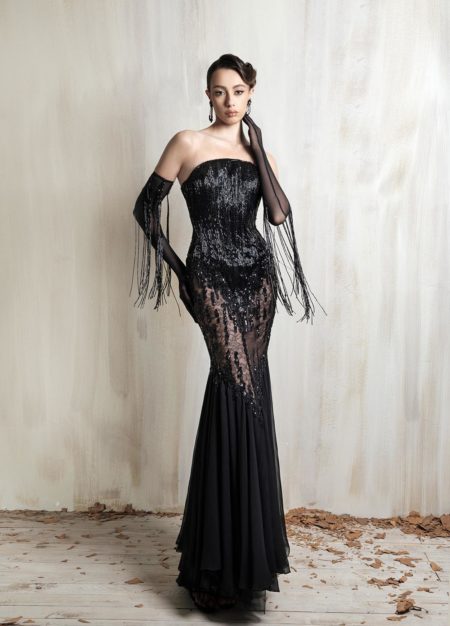 Black strapless lace gown with sheer gloves and fringe details.