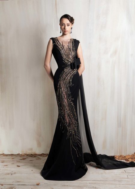 Black gown with golden cascade embroidery and sleek cape detail.