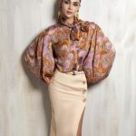 Statement silk blouse with voluminous sleeves and tailored beige skirt.