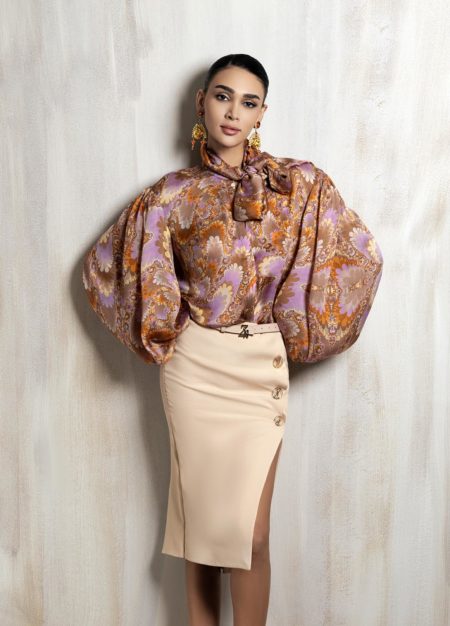 Statement silk blouse with voluminous sleeves and tailored beige skirt.
