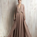 Flowing taupe gown with gold-embroidered neckline and cape sleeves.