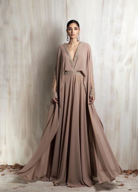Flowing taupe gown with gold-embroidered neckline and cape sleeves.