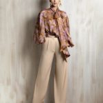 Printed silk blouse paired with relaxed beige wide-leg trousers