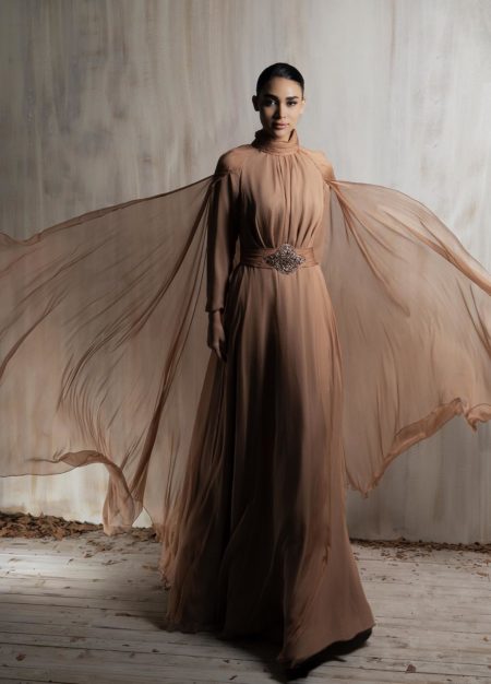 Flowing mocha chiffon gown with ethereal cape sleeves.