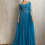 Turquoise embellished gown with graceful flowing cape.